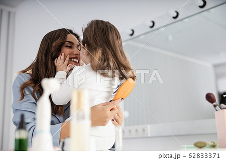 Happy pretty mom helping her daughter with hair 62833371