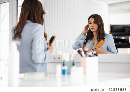 Pretty young woman combing her hair at home 62833683