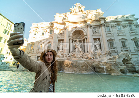 Selfie of young woman on the background of Trevi Fountain, Rome, Italy. Fontana di Trevi is one of the main tourist attractions of Rome. People visit the Rome landmark. Traveling and vacation in Rome. 62834536