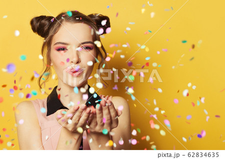 Happy cheerful girl blowing confetti on colorful 62834635