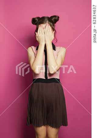 Young woman hiding behind her hands on bright pink Young woman hiding behind her hands on bright pink 62834637