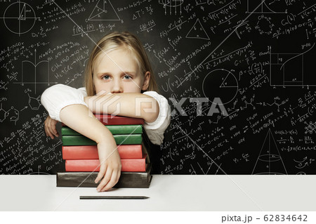 Tired child with books thinking on chalkboard Tired child with books thinking on chalkboard 62834642