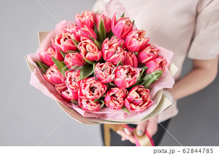 Crimson color tulips in woman hand. Spring bouquet of red tulips in hands. Bunch of fresh cut spring flowers 62844785