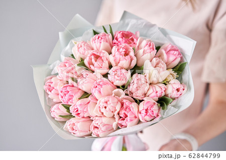 Pink pastel color tulips in woman hand. Young beautiful woman holding a spring bouquet. Bunch of fresh cut spring flowers in female hands 62844799
