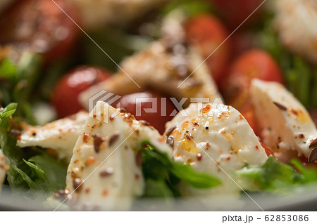 Closeup salad with cherry tomatoes, mozzarella and frisee leaves in white bowl on concrete background 62853086