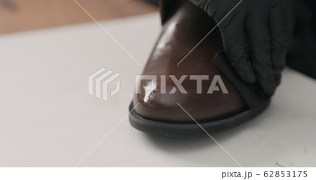 man hands in black gloves applying protective cream to brown leather chukka boots 62853175