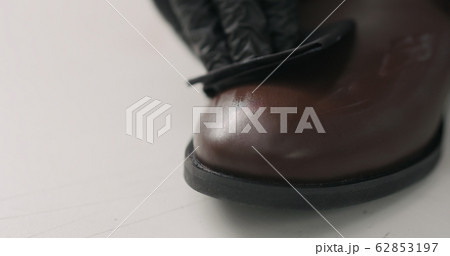 man hands in black gloves applying protective cream to brown leather chukka boots 62853197