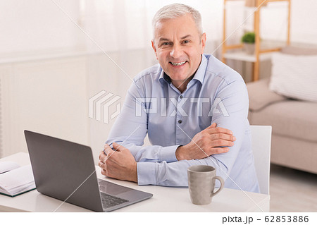 Senior man using laptop at office and looking at camera Senior man using laptop at office and looking at camera 62853886