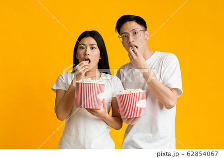 Shocked asian guy and girl eating popcorn, watching movie 62854067