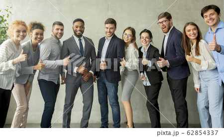Cheerful young business team showing thumbs up 62854337