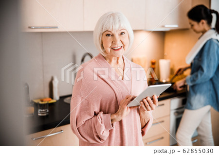 Lovely old woman holding modern gadget and smiling Lovely old woman holding modern gadget and smiling 62855030