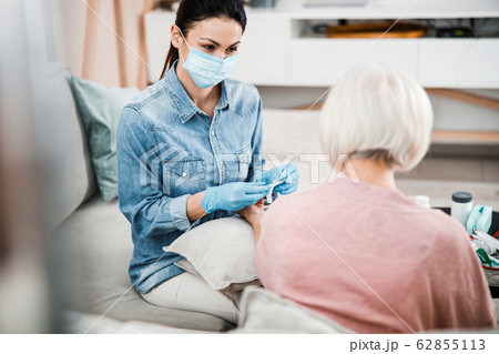 Female doctor sitting on couch with old woman Female doctor sitting on couch with old woman 62855113