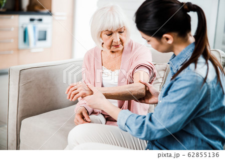 Female physician checking arm of elderly woman Female physician checking arm of elderly woman 62855136