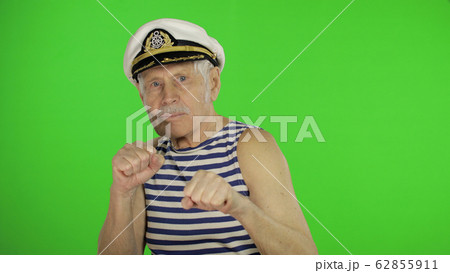 Elderly sailor man is angry and shows fists. Sailorman on chroma key background Elderly sailor man is angry and shows fists. Sailorman on chroma key background 62855911