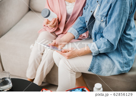 Young lady using digital tablet while sitting on couch with old woman 62856129