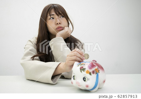 貯金箱の前で考え事をする若い女性 貯金箱の前で考え事をする若い女性 62857913