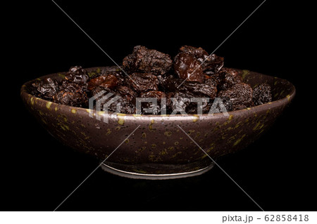 Dried dark raisin isolated on black glass Dried dark raisin isolated on black glass 62858418