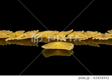 Yellow farfalle pasta isolated on black glass 62858442