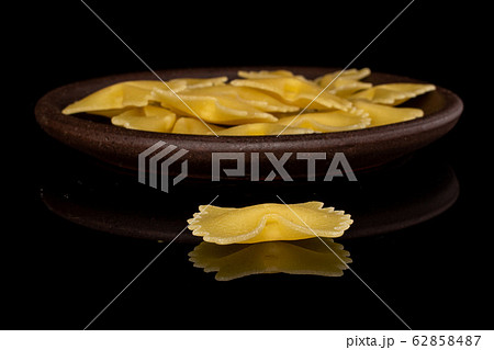 Yellow farfalle pasta isolated on black glass 62858487