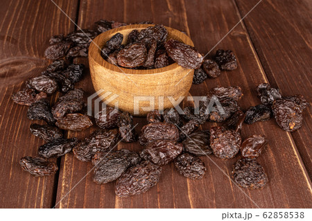 Dried dark raisin on brown wood Dried dark raisin on brown wood 62858538