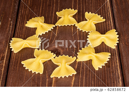 Yellow farfalle pasta on brown wood Yellow farfalle pasta on brown wood 62858672