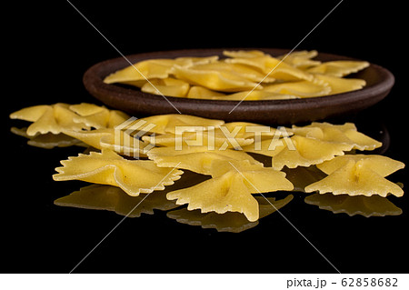 Yellow farfalle pasta isolated on black glass Yellow farfalle pasta isolated on black glass 62858682
