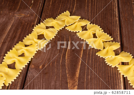 Yellow farfalle pasta on brown wood Yellow farfalle pasta on brown wood 62858711