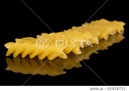 Yellow fusilli pasta isolated on black glass 62858722