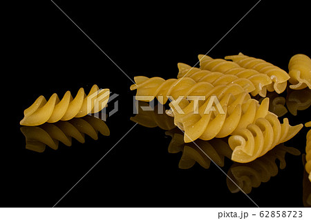 Yellow fusilli pasta isolated on black glass 62858723