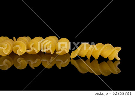 Yellow fusilli pasta isolated on black glass 62858731