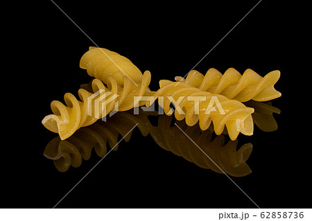 Yellow fusilli pasta isolated on black glass 62858736
