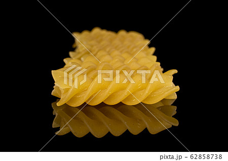 Yellow fusilli pasta isolated on black glass 62858738