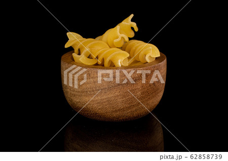 Yellow fusilli pasta isolated on black glass 62858739