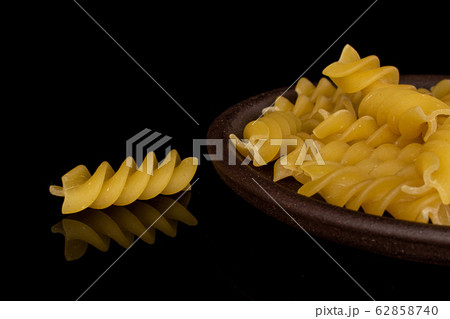 Yellow fusilli pasta isolated on black glass Yellow fusilli pasta isolated on black glass 62858740