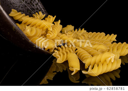 Yellow fusilli pasta isolated on black glass 62858781
