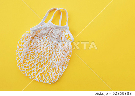 Reusable eco friendly cotton net bag for grocery shopping and food storage on yellow background. 62859388