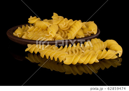 Yellow fusilli pasta isolated on black glass 62859474