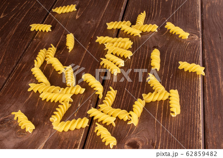 Yellow fusilli pasta on brown wood Yellow fusilli pasta on brown wood 62859482