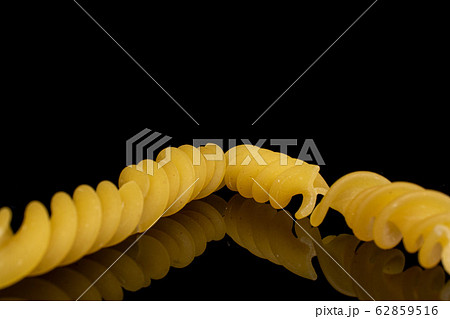 Yellow fusilli pasta isolated on black glass Yellow fusilli pasta isolated on black glass 62859516