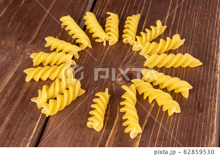 Yellow fusilli pasta on brown wood 62859530