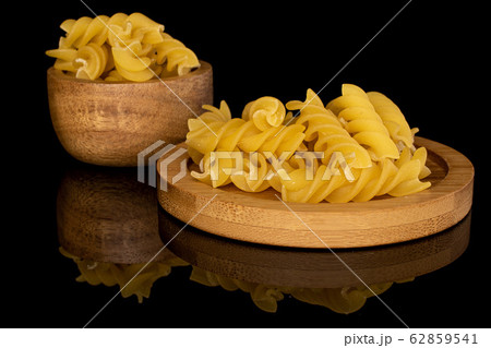 Yellow fusilli pasta isolated on black glass 62859541