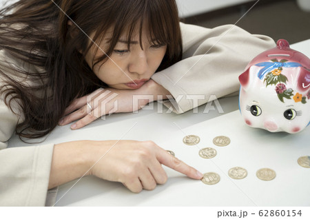 硬貨を触る若い女性と貯金箱 硬貨を触る若い女性と貯金箱 62860154