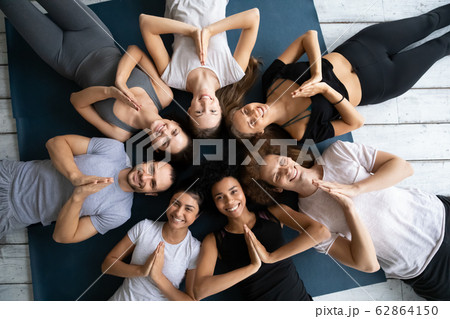 Above view people in sportswear lying on mats showing Namaste 62864150