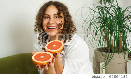 Portrait of pretty middle-aged woman with curly hair with grapefruit 62864185