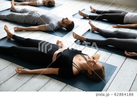 People resting after yoga workout lying in Shavasana Pose 62864186