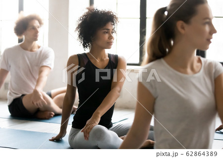 African woman with associates practicing yoga seated in lotus pose African woman with associates practicing yoga seated in lotus pose 62864389