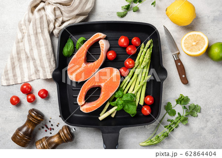 Uncooked salmon steaks with vegetables on a grill pan 62864404
