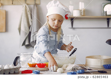 Little girl in a white shef hat cook the dough for cookies Little girl in a white shef hat cook the dough for cookies 62865463