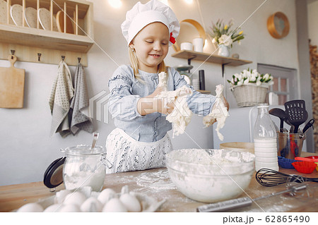 Little girl in a white shef hat cook the dough for cookies Little girl in a white shef hat cook the dough for cookies 62865490