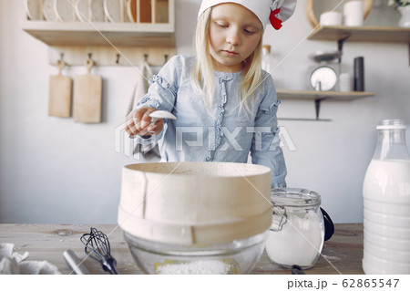 Little girl in a white shef hat cook the dough for cookies Little girl in a white shef hat cook the dough for cookies 62865547